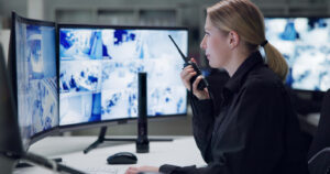 Security Guard watching monitors while talking on radio